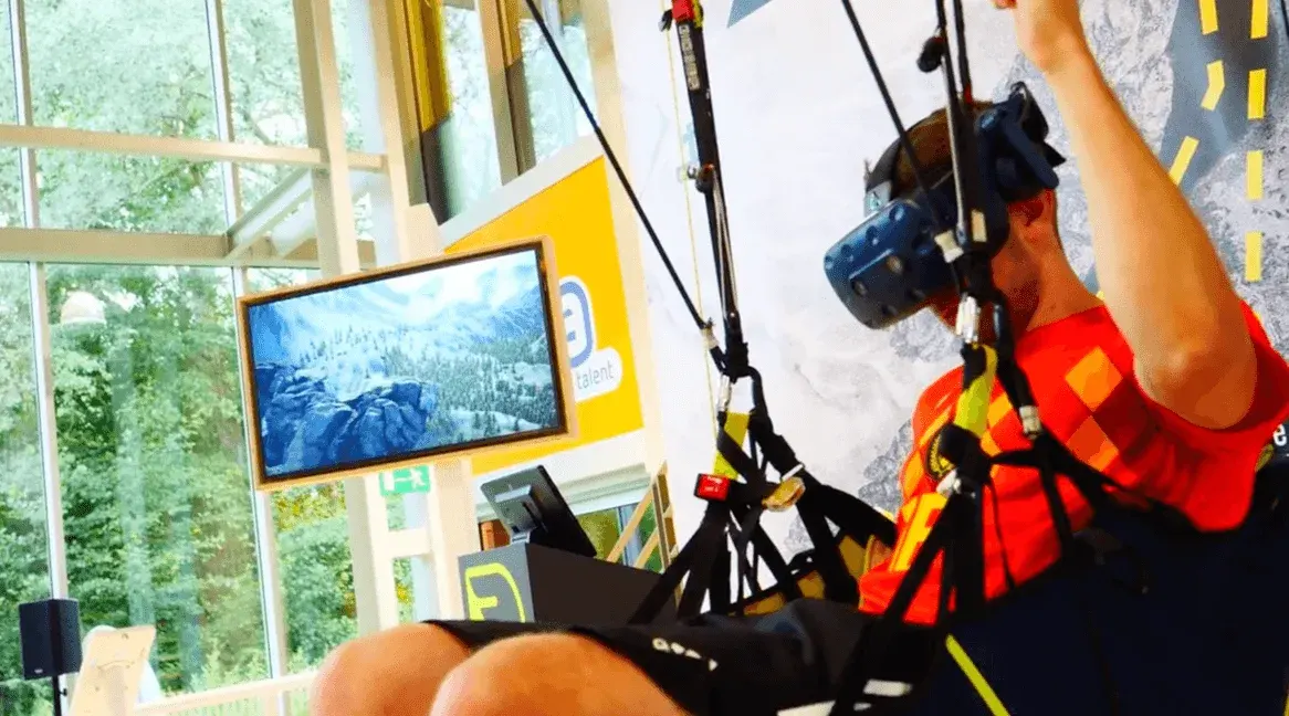 Participant in a red shirt using the VR paragliding headset and steering handles at Technopolis.