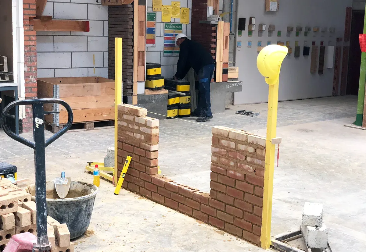 Masonry training space with practice brick walls, tools and construction materials.